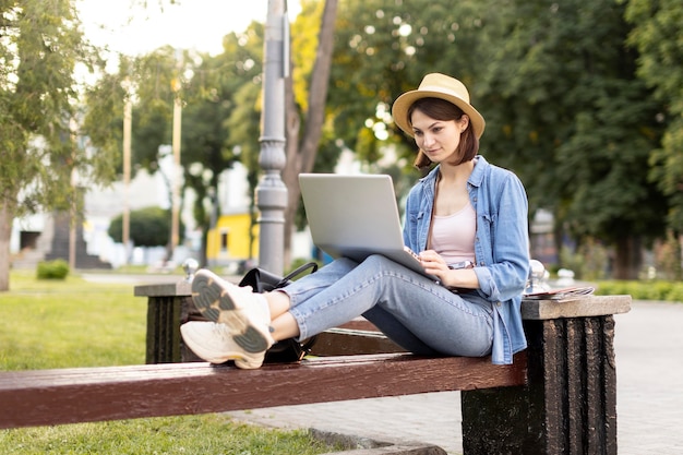 Free photo stylish tourist with hat checking laptop outdoors