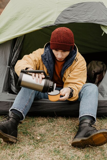 Stylish traveller pouring drink in cup