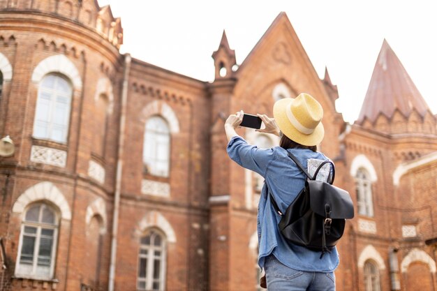 Stylish traveller with hat taking pictures on holiday