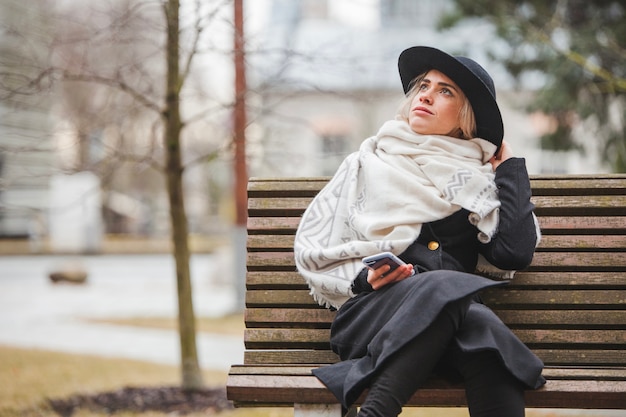 Free photo stylish woman on bench on a rainy day