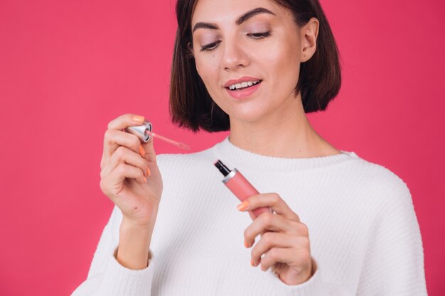 Stylish woman in casual white sweater on pink red wall