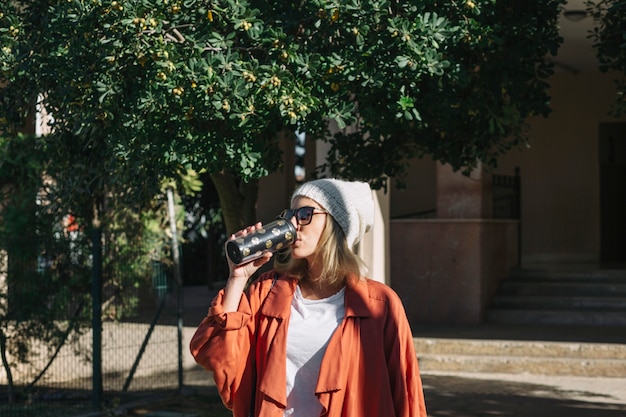 Stylish woman drinking on street