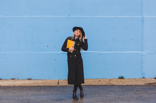 Free photo stylish woman in front of blue wall