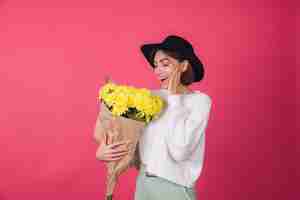 Free photo stylish woman in hat and casual white sweater on red wall