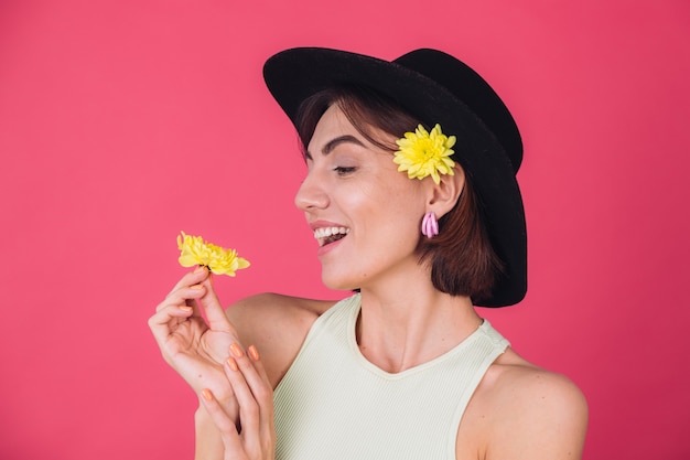 Stylish woman in hat, smiling with two yellow asters, spring mood, happy emotions isolated space