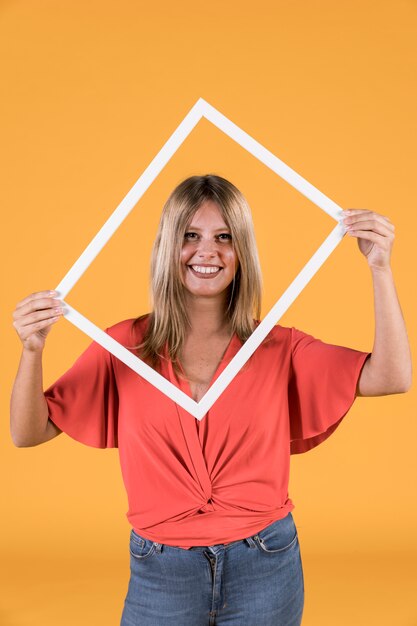 Stylish woman holding white border photo frame in front of her face