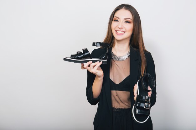 stylish woman isolated in black suit holding pait of shoes