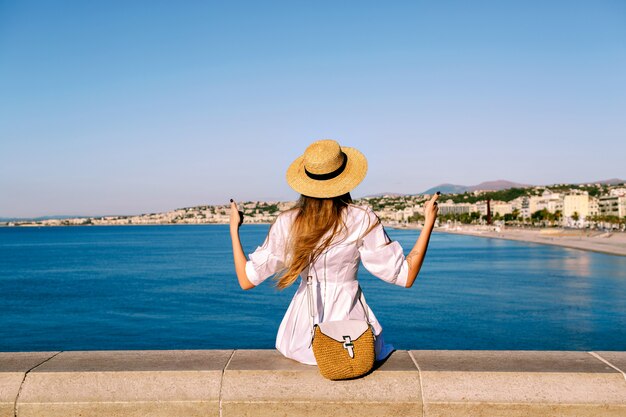 ニースの素晴らしい景色の前でポーズをとってスタイリッシュな女性