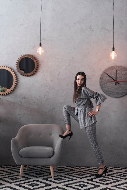 Stylish woman posing near armchair