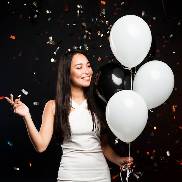 Stylish woman posing with balloons at party