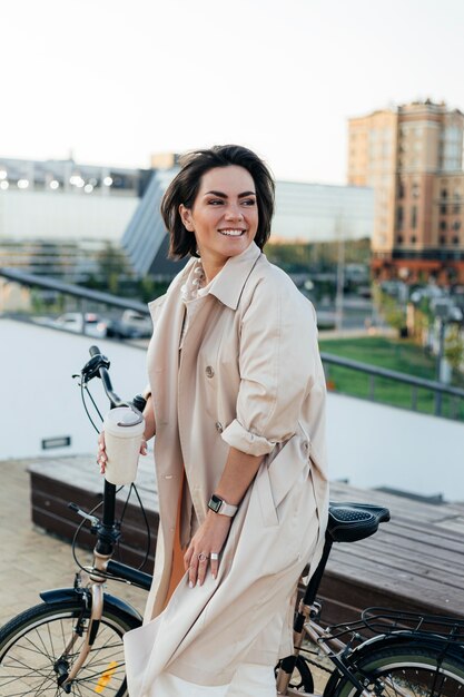 Stylish woman posing with bicycle outdoors