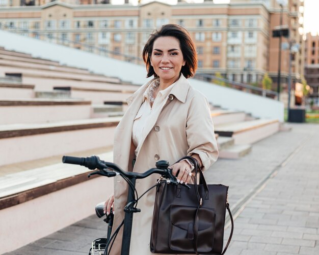 Stylish woman posing with bicycle outdoors