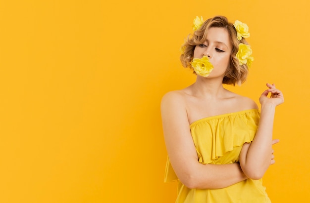 Stylish woman posing with flower covering her mouth