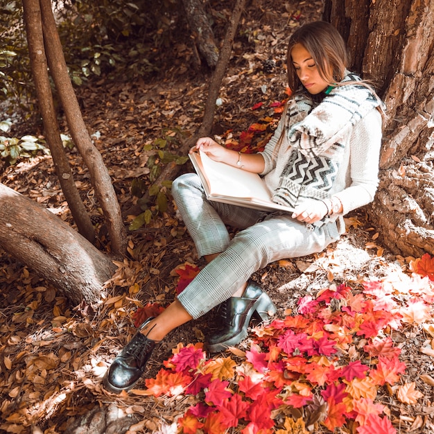 Foto gratuita lettura alla moda della donna nella foresta di autunno