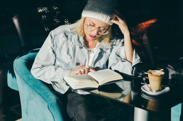 Стильная женщина, читающая в кафе