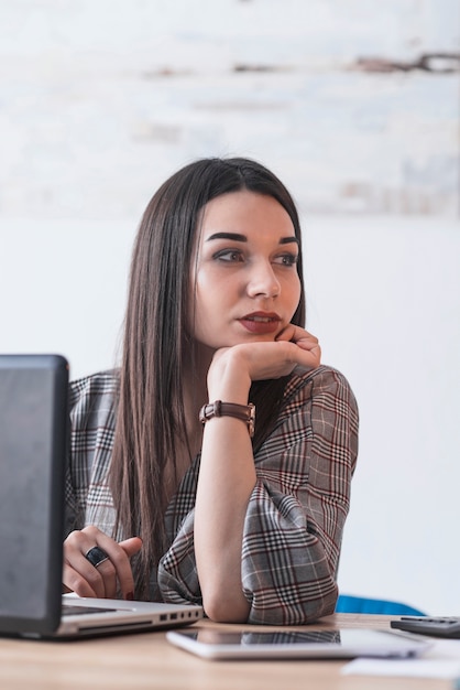 Foto gratuita donna alla moda che si siede vicino al computer portatile