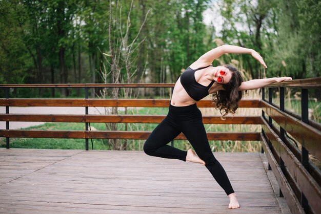 Stylish woman stretching muscles with holding railing