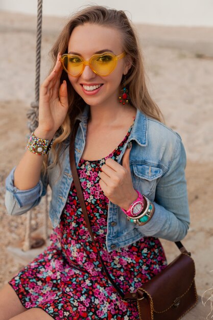 Stylish woman in summer dress vacation on beach in colorful yellow sunglasess smiling happy