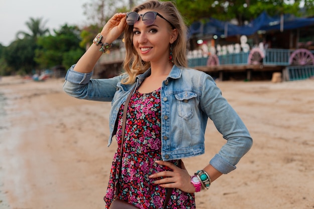 Stylish woman in summer dress vacation walking on beach with sunglasses