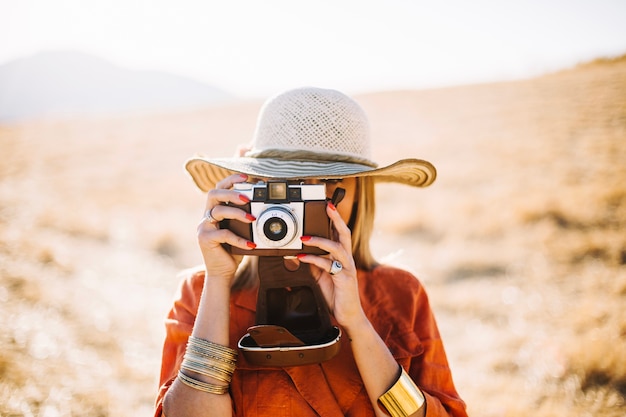 レトロカメラを砂漠で使っているスタイリッシュな女性