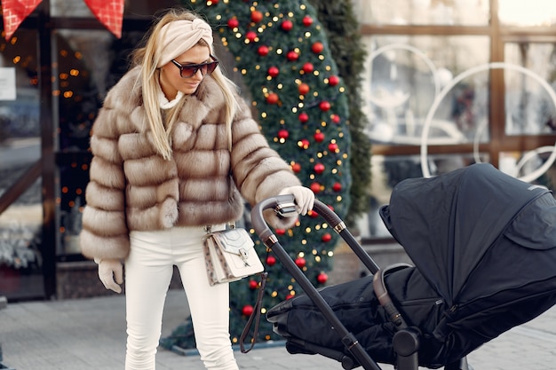 Stylish woman walking in a city with carriage