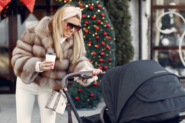 Stylish woman walking in a city with carriage