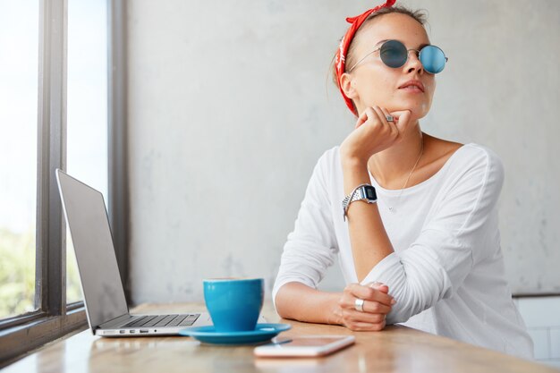 Stylish woman wearing bandana sitting in cafe