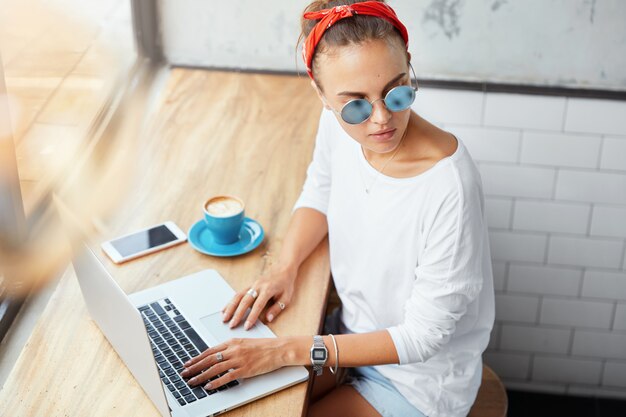 Stylish woman wearing bandana sitting in cafe