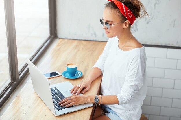 Stylish woman wearing bandana sitting in cafe