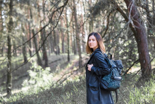 Stylish woman with backpack in forest