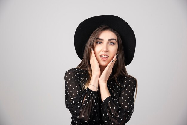 Stylish woman with black hat looking at camera.