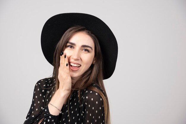 Stylish woman with black hat smiling happily.