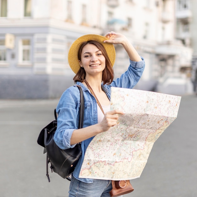 Stylish woman with hat holding local map