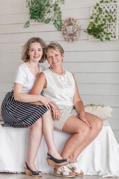 Stylish woman with her mother sitting on sofa looking at camera