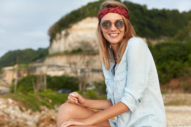 Stylish woman with sunglasses sitting on the beach