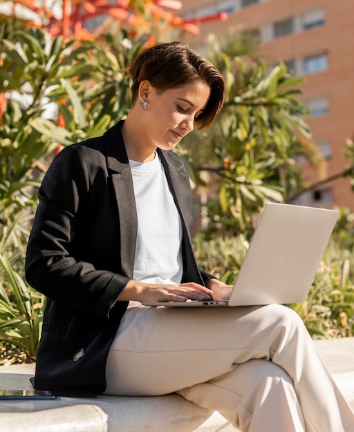 Stylish woman working on laptop outside