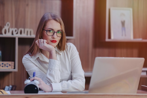 Foto gratuita la donna alla moda lavora ad uno scrittorio del computer portatile in un ufficio moderno