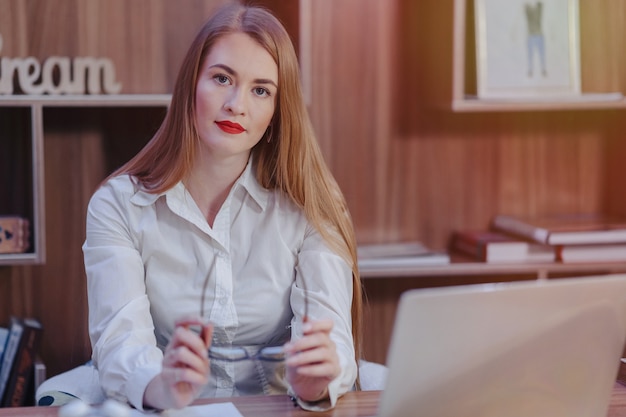 Foto gratuita la donna alla moda lavora ad uno scrittorio del computer portatile in un ufficio moderno