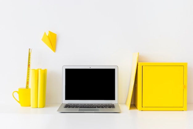 Stylish workspace with laptop and yellow metal box