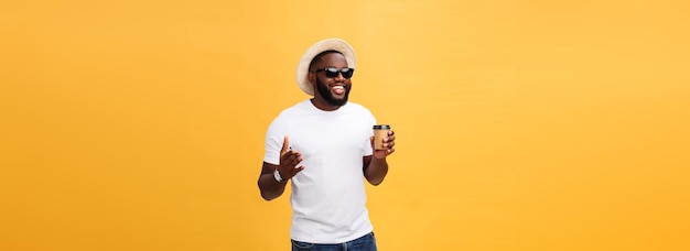 Stylish young african american man holding cup of take away coffee isolated over yellow background