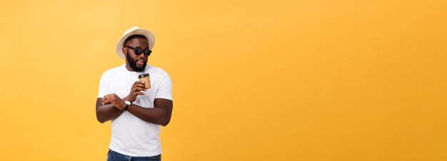 Стильный молодой африканский американец, держащий чашку кофе на вынос, изолированный на желтом фоне