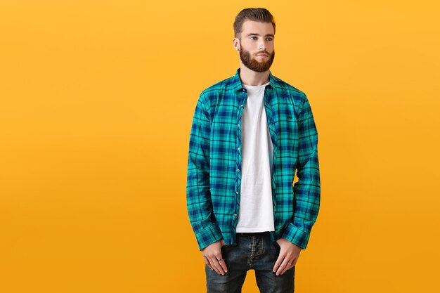 Stylish young bearded man in checkered shirt posing on yellow background fashion trend style apparel