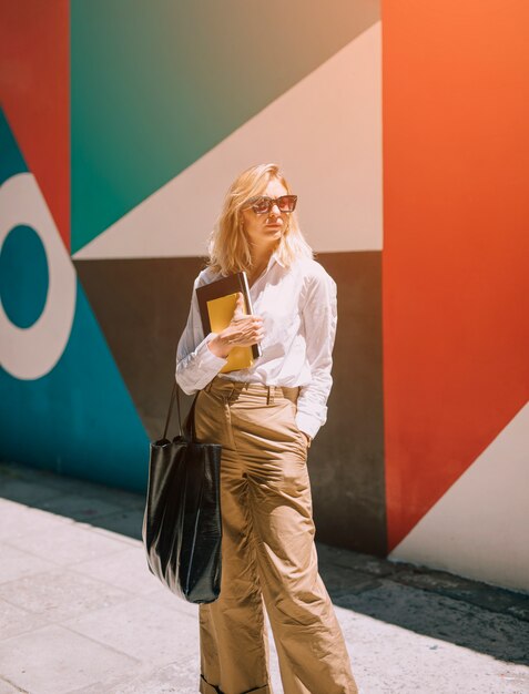 Stylish young beautiful businesswoman standing in front of painted wall