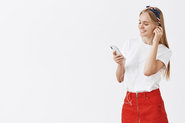 Stylish young blond girl posing against the white wall