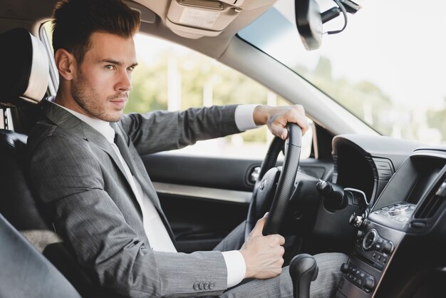Stylish young businessman driving car