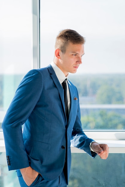 Stylish young businessman posing near the window