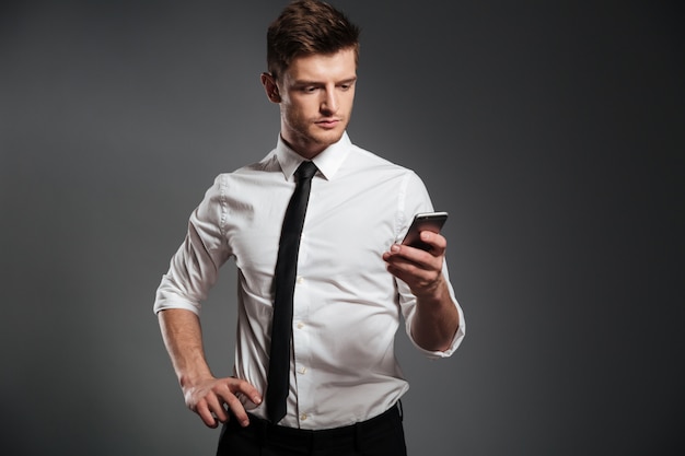 Стильный молодой бизнесмен, с помощью мобильного телефона, стоя