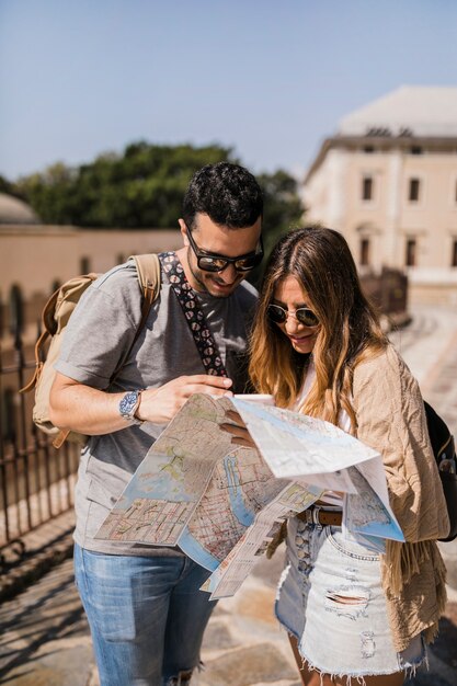Stylish young couple on vacation looking at map