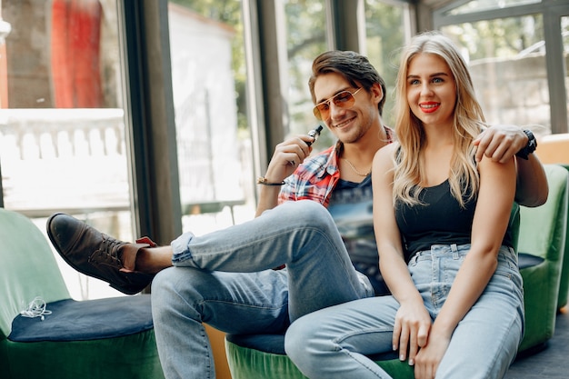 Stylish young couple with vape in a cafe