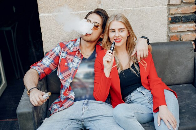 Stylish young couple with vape in a cafe